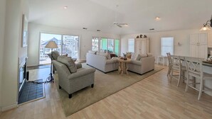 A spacious living area with a sofa, chairs, a dining table, and a kitchen area.