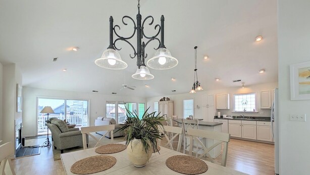 A spacious living area with a dining table, chairs, and a chandelier.