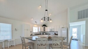 A modern kitchen with white cabinetry, a central island with bar stools, and pendant lighting.