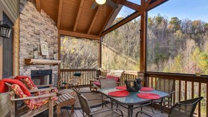 A covered outdoor patio with a stone wall, wooden deck, and a table with chairs.