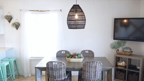 A dining area with a dark wooden table, wicker chairs, and a hanging light fixture. - "Emerald Hideaway" Cozy Luxurious Condo, Community Pool! (Navarre)