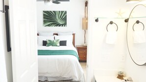 A bedroom with a bed, a nightstand, and a wall-mounted lamp. - "Emerald Hideaway" Cozy Luxurious Condo, Community Pool! (Navarre)