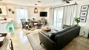 A modern living room with a sofa, dining area, and a ceiling fan. - "Emerald Hideaway" Cozy Luxurious Condo, Community Pool! (Navarre)