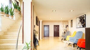 Um hall de hotel com escadas, área de estar e obras de arte nas paredes.