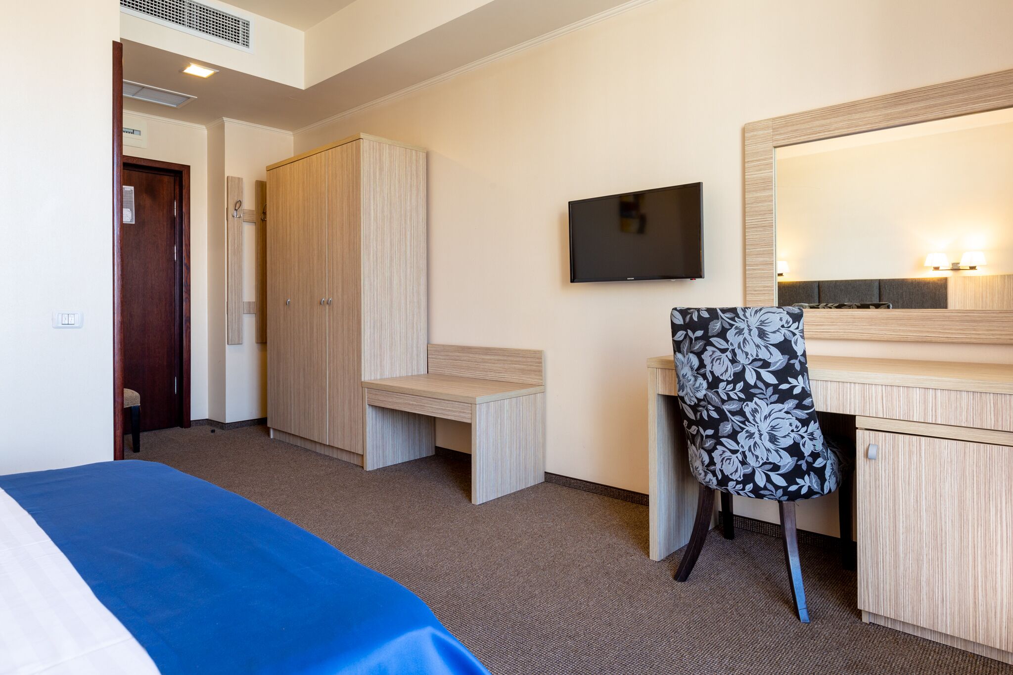 Una habitación de hotel con una cama, un escritorio, una silla, un televisor y un armario.