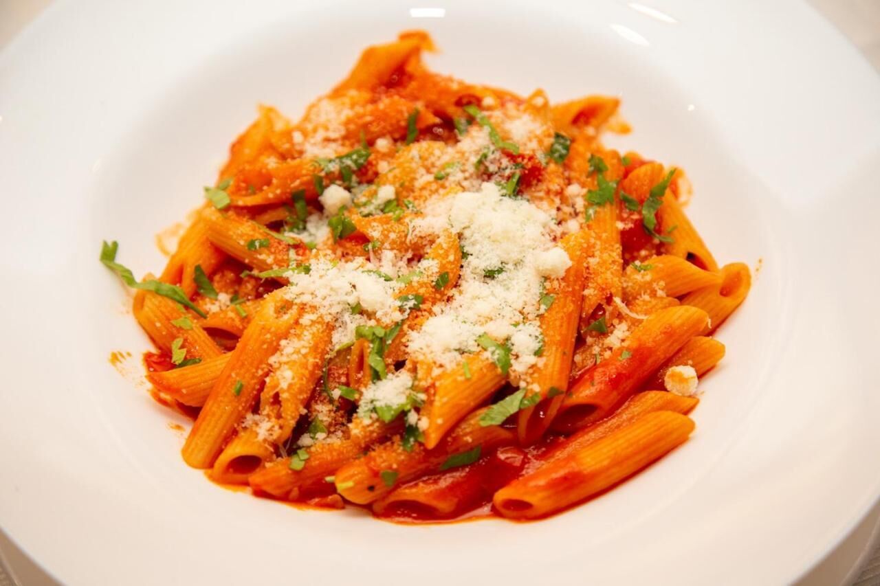 Un piatto di pasta con salsa di pomodoro, guarnito con formaggio e erbe aromatiche.