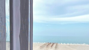 Uma varanda com vista para a praia e uma fileira de cadeiras e guarda-sóis.