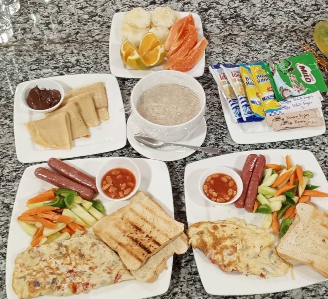 A table with various food items including sandwiches, hot dogs, and a bowl of soup.