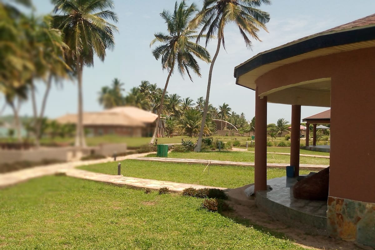 A well-maintained outdoor area with a covered seating area, a pathway, and palm trees.