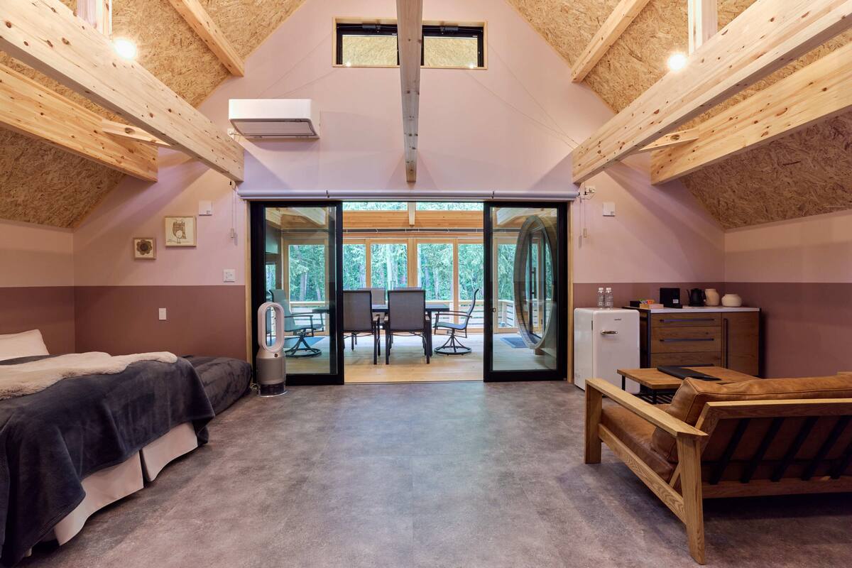 A cozy bedroom with a bed, a small desk, and a wooden bench.