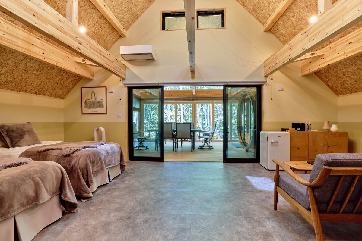 A cozy room with two beds, a dining table, and a view of the outdoors.