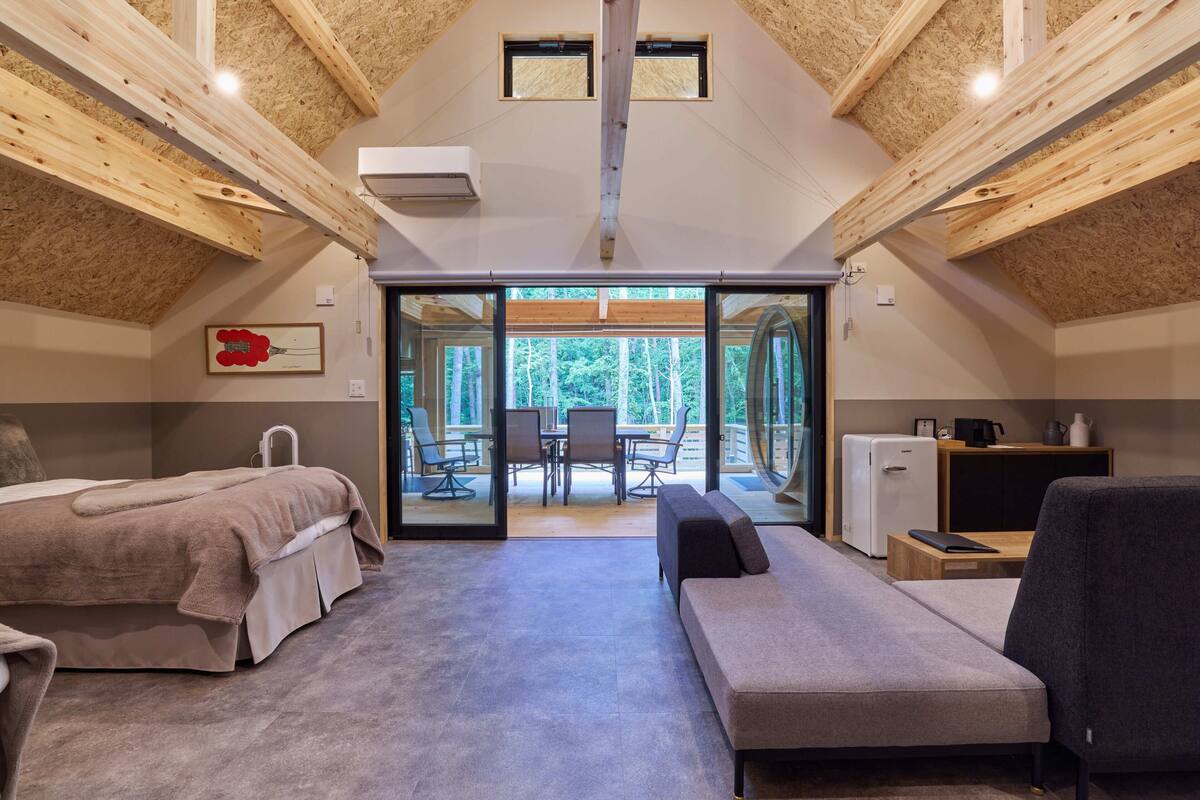 A cozy room with a bed, a sofa, and a dining area with a table and chairs.