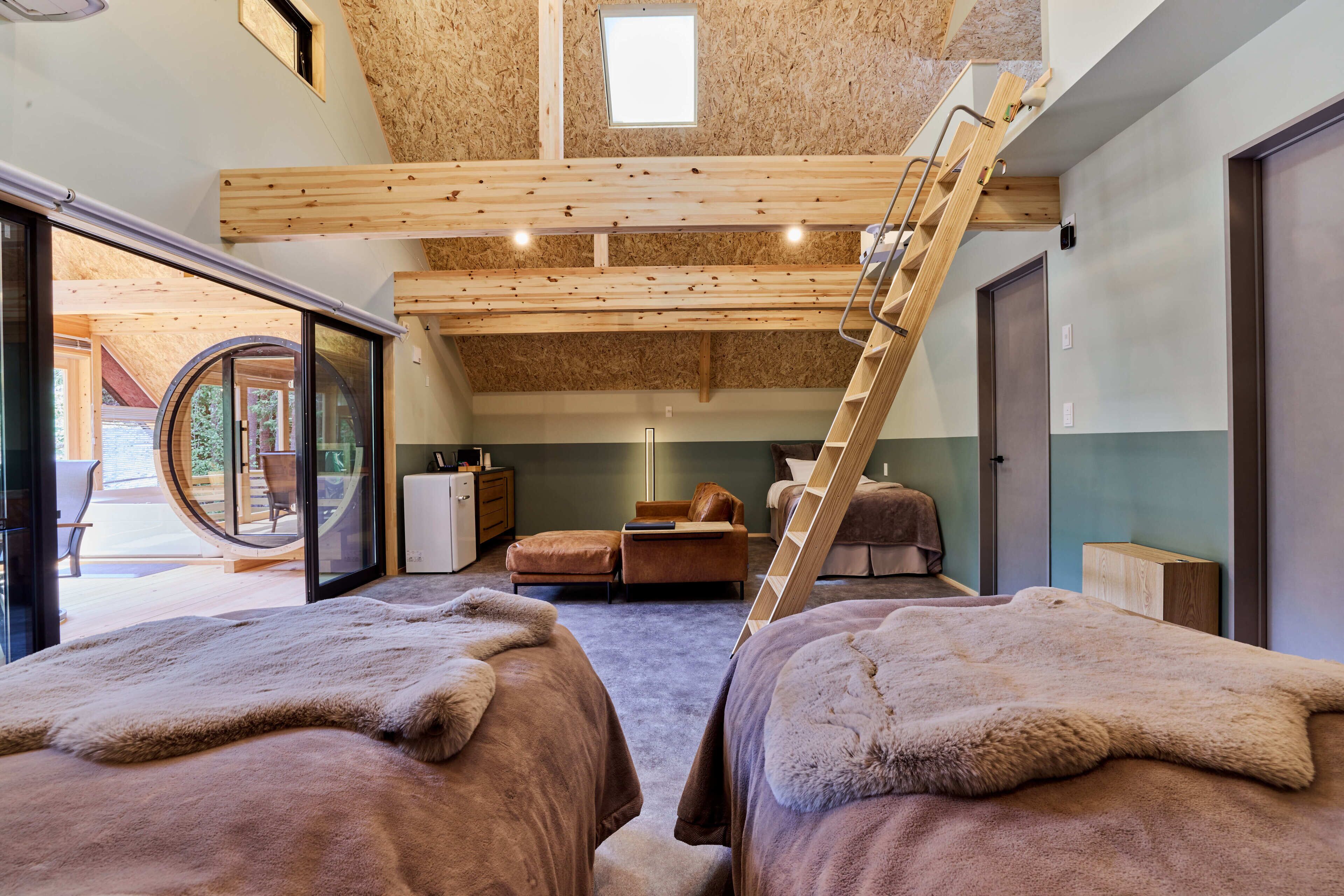 Een gezellige kamer met een hoogslaper, een trapje, een zithoekje en uitzicht op de omgeving.