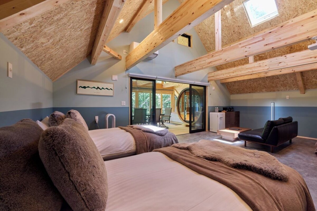 Un dormitorio con dos camas, un sofá y una puerta corrediza de vidrio que da a un balcón.