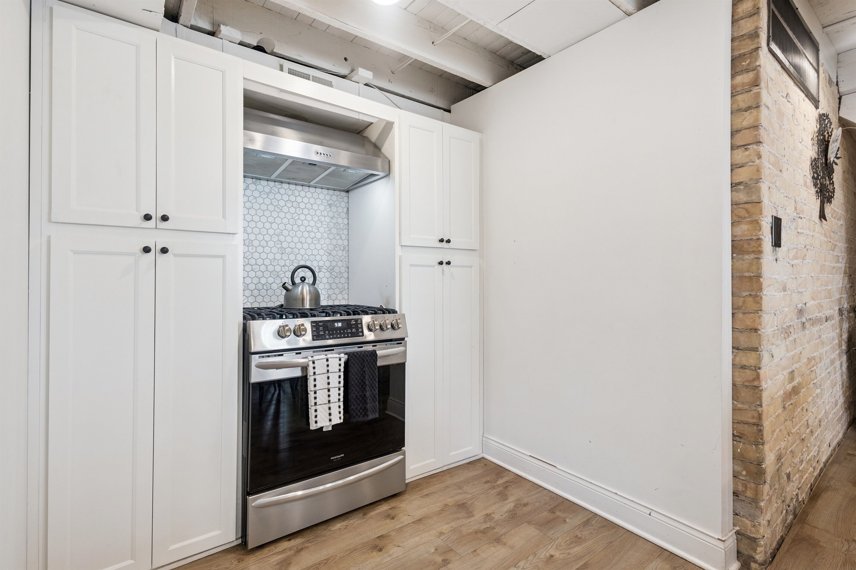 A kitchen with white cabinets, a stainless steel stove, and a tiled backsplash.