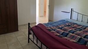 A bedroom with a bed, a wooden wardrobe, and a door leading to another room. - Relaxation house (Marche)