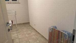 A narrow hallway with tiled flooring, a metal rack, and a radiator covered in plastic. - Relaxation house (Marche)
