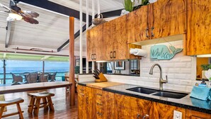 Una cocina con armarios de madera, encimera negra y vistas al océano.