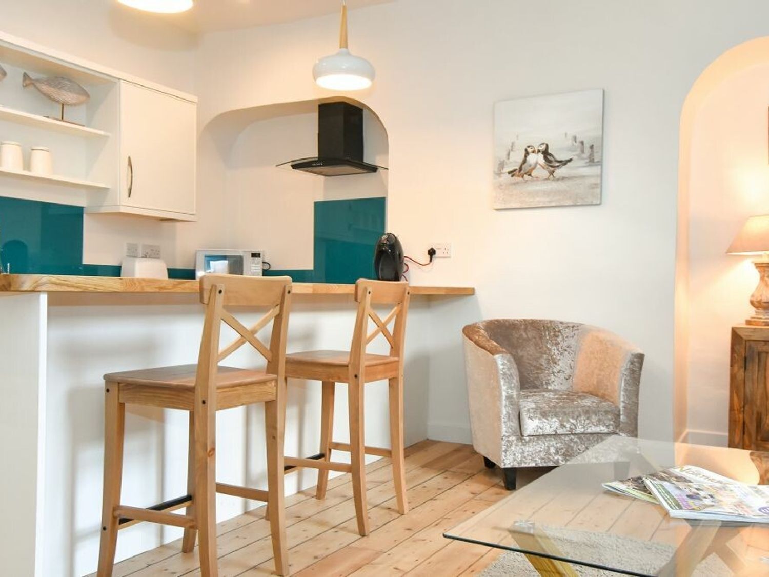 Una cocina moderna con sillas de madera, una barra y una zona de estar con un sillón acolchado.