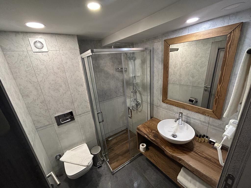 A modern bathroom with a glass shower enclosure, a wooden vanity with a sink, and a large mirror.