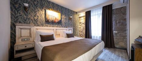 Quarto de hotel com uma cama grande, parede de destaque em pedra, lareira e parede de pedra ao lado da janela.