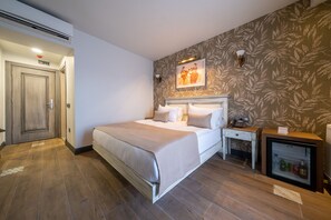 Une chambre d’hôtel comprenant un lit, une table de chevet, un petit réfrigérateur et une œuvre d’art accrochée au mur.
