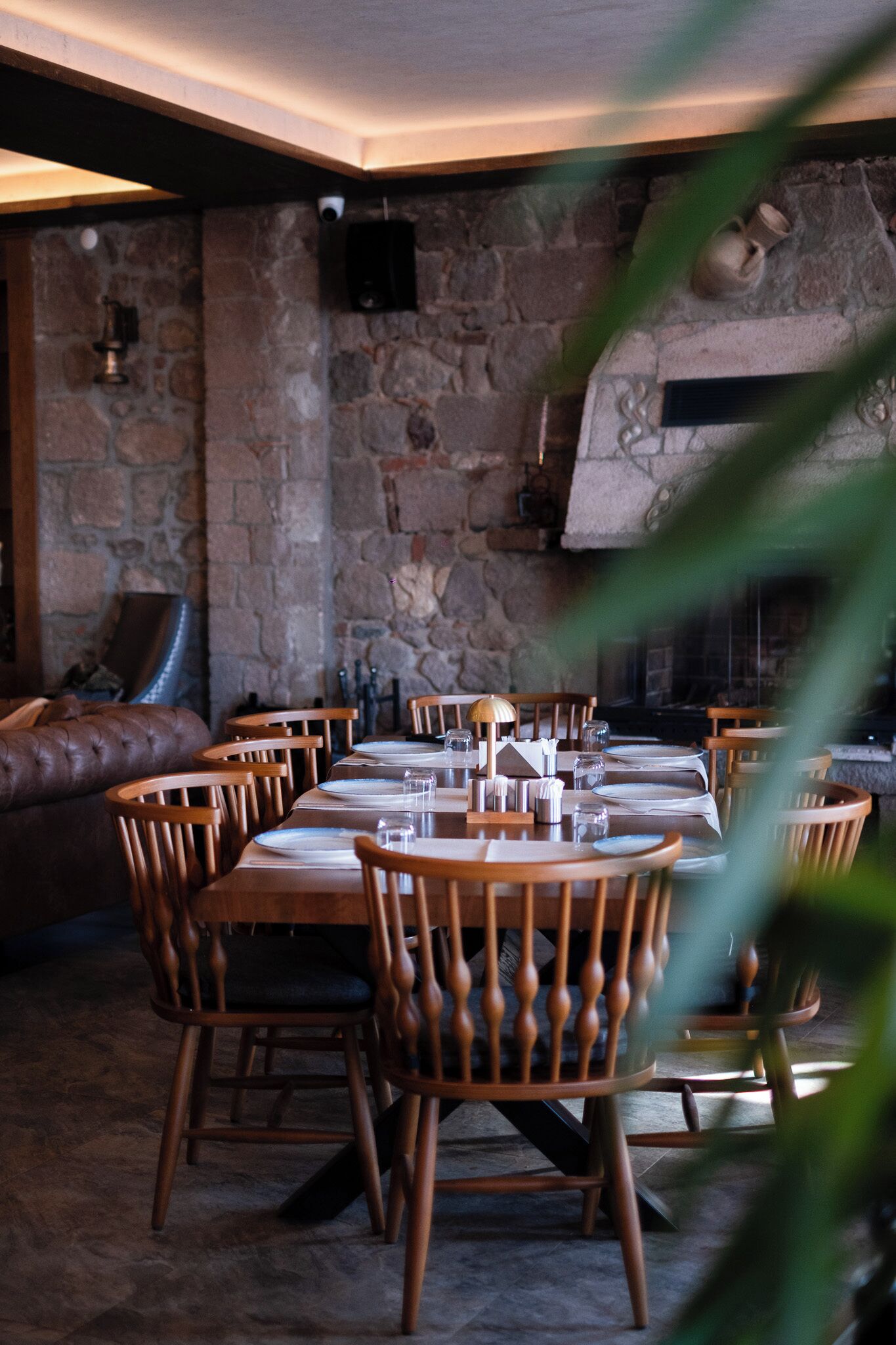 Un restaurant avec un mur en pierre, des chaises en bois et une cheminée.