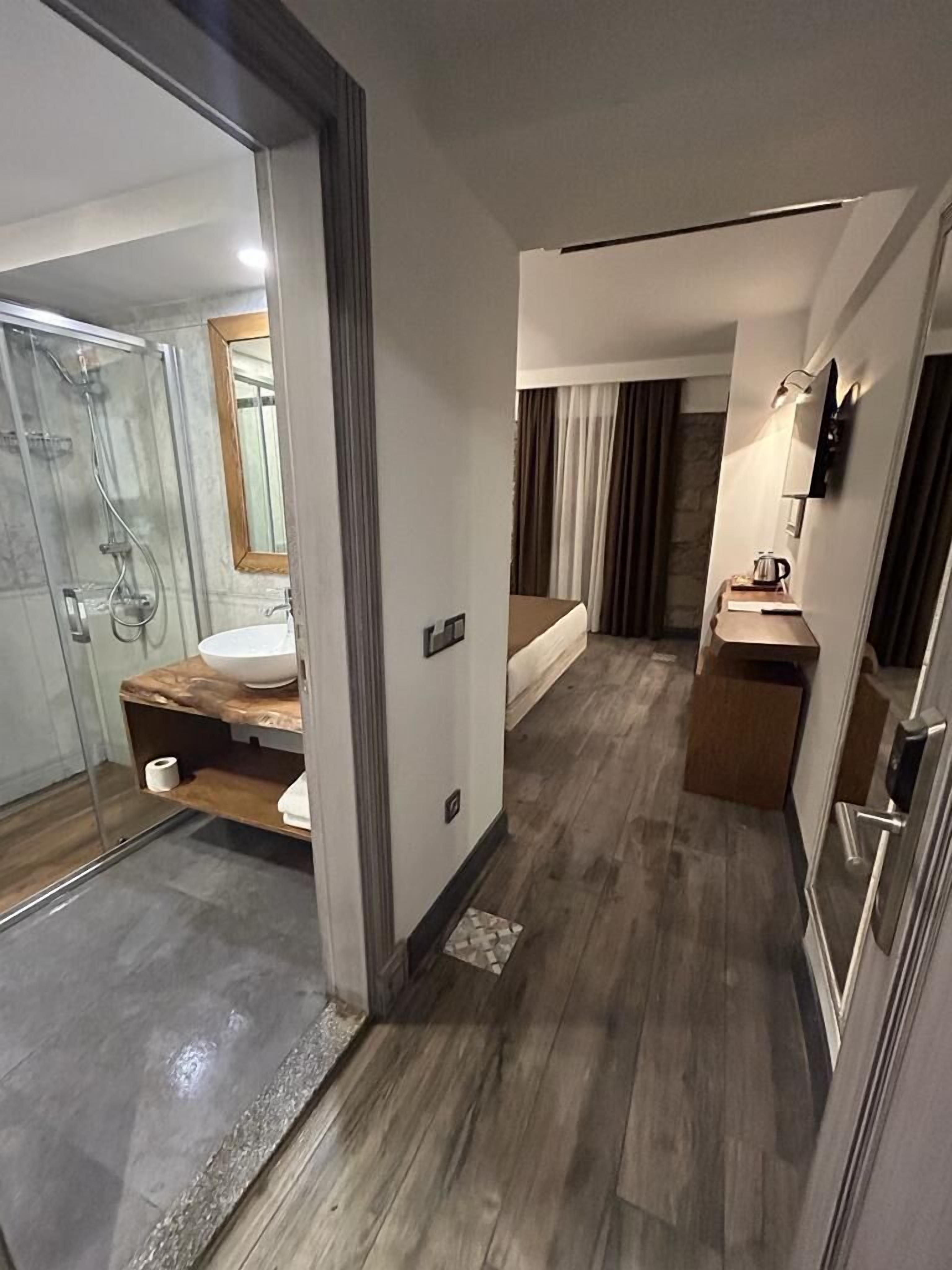 A modern bathroom with a glass shower enclosure, a wooden vanity, and a large mirror.