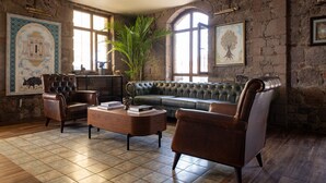 A cozy living room with a green sofa, leather armchairs, and a wooden coffee table. - Assos Troy Port Hotel (Ayvacik)