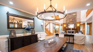Un amplio salón con una mesa de comedor de madera, un espejo grande y una chimenea de piedra.