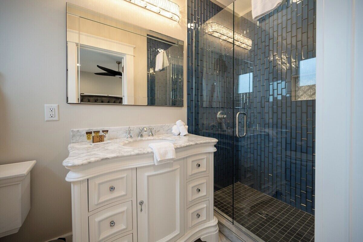 A bathroom with a white vanity, a large mirror, and a glass-enclosed shower area.