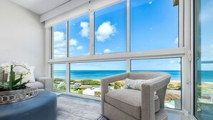 Un salón moderno con un ventanal grande que ofrece vistas al océano y a la playa.