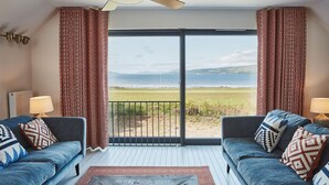 Ein Zimmer mit zwei Sofas, die eine große Schiebetür zu einem Balkon mit Seeblick und Bergblick zeigen.