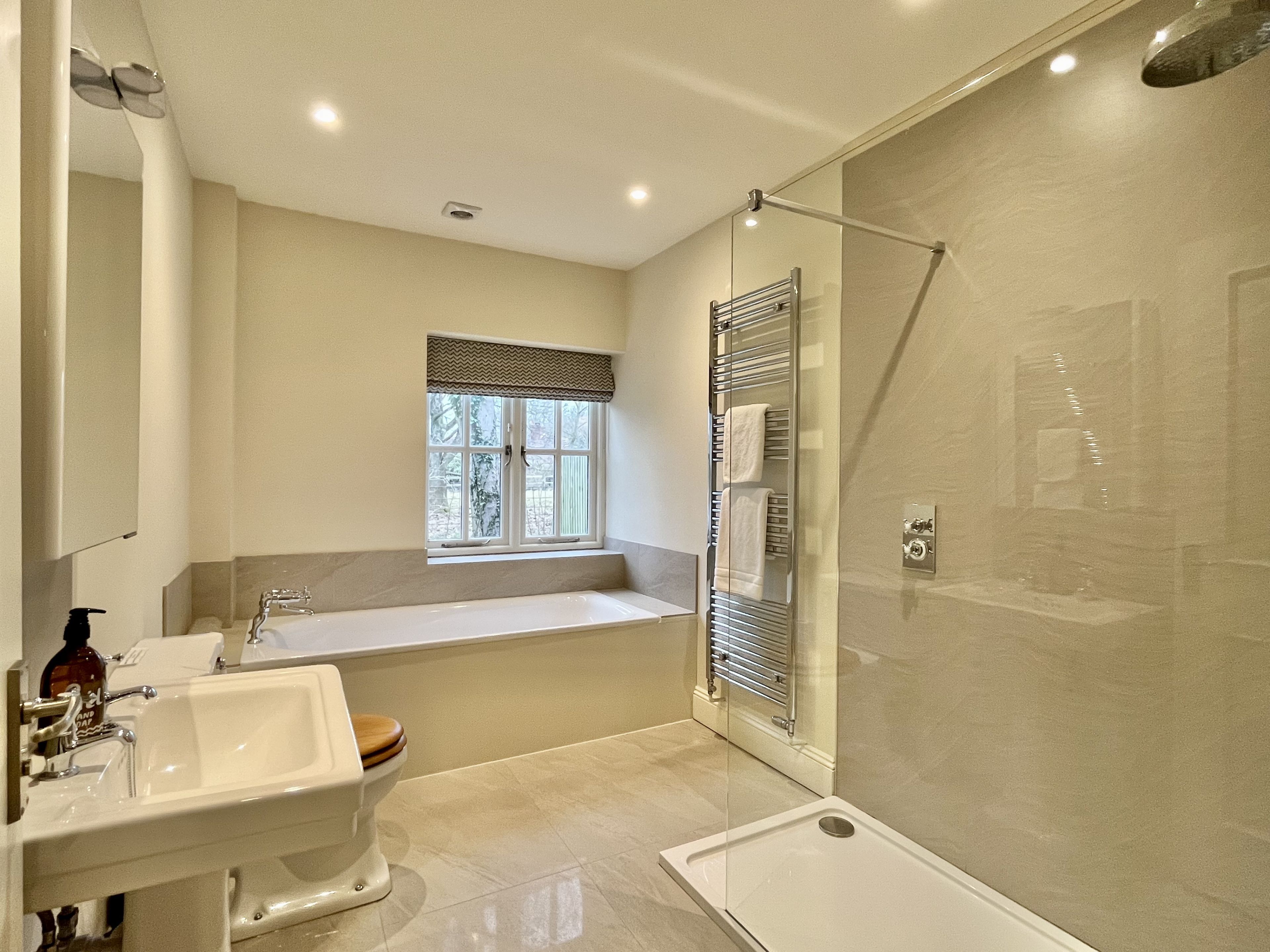 A modern bathroom with a bathtub, toilet, and shower.