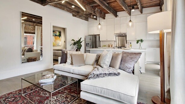 Un salon moderne avec une table basse en verre, un canapé blanc et un tapis à motifs rouges.