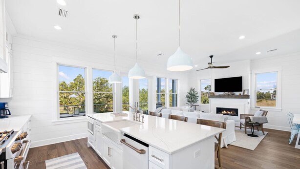 A modern kitchen with white cabinetry, a large island, and a dining area with a fireplace.