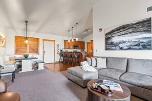 A modern living room with a grey sofa, a coffee table, and a kitchen in the background.