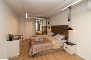 Une chambre moderne avec un grand lit, des tables de chevet, un miroir et une plante en pot.