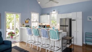 A kitchen with a bar area, white cabinets, and a ceiling fan.