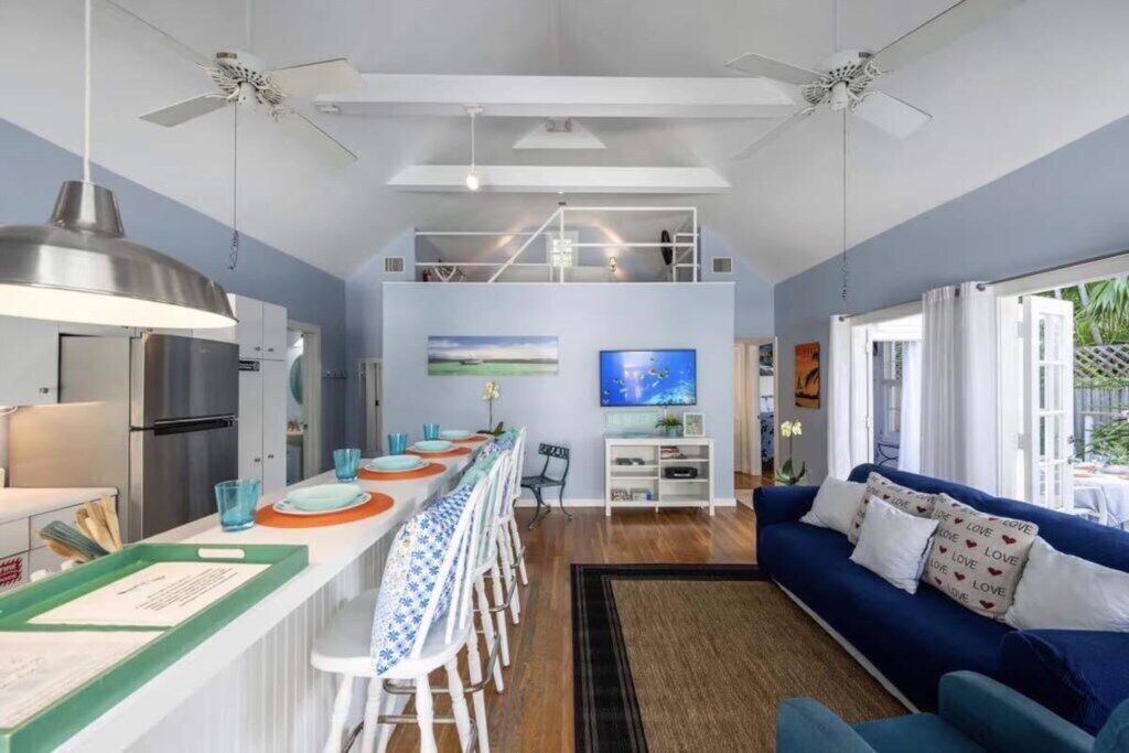 Une cuisine moderne avec un coin repas, un canapé bleu et un ventilateur de plafond.