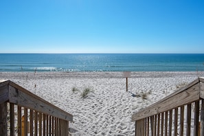 A beach with wooden walkways leading to the shore, clear blue sky, and calm ocean.