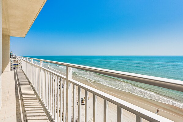 A balcony with a view of the beach and ocean.