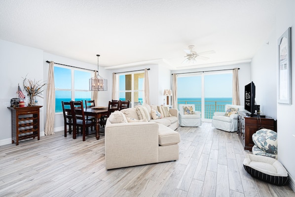 Relax in this stylish living room with a sofa, armchair, and dining area, offering a balcony with ocean views.