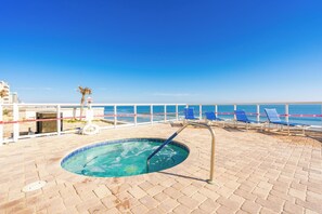 Relax by the ocean-view pool surrounded by lounge chairs and a palm tree.