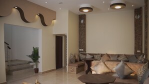 A modern living area with a sofa set, a coffee table, and a potted plant. - Petra Passion Inn (Wadi Musa)