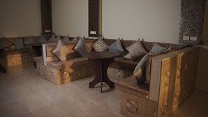 A seating area with a low, curved bench and a small round table. - Petra Passion Inn (Wadi Musa)