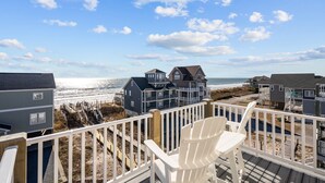 A beachfront property with a wooden deck, white chairs, and a view of the ocean and beach houses. - The Hamptons #139 Brand new, Oceanfront B,  Hot Tub, Com. Pool! (North Topsail Beach)