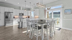 A modern kitchen with white cabinetry, stainless steel appliances, and a central island with seating. - The Hamptons #139 Brand new, Oceanfront B,  Hot Tub, Com. Pool! (North Topsail Beach)