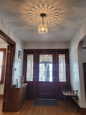 A foyer with a wooden door, a bench, and a chandelier.