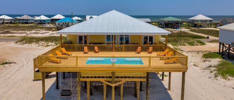 Una propiedad frente a la playa con piscina, sillas de deck y un patio cubierto.